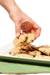 A plate of oatmeal chocolate chip cookies with a hand taking two.