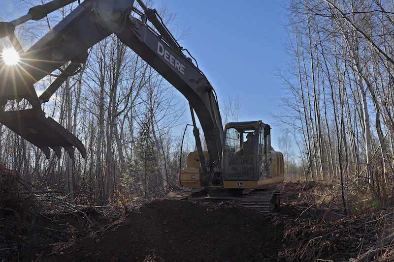 Corporal Will Morgan-Boudreau, Heavy Equipment Troop with 4 Engineer Support Regiment uses an excavator with a claw to clear stumps while clearing brush and trees from a proposed ATV and snowmobile trail outside Bathurst New Brunswick on 7 November 2016 during Exercise Nihilo Sapper 16. LH01-2016-025-048 Photo by WO Jerry Kean/5 Cdn Div HQ Public Affairs